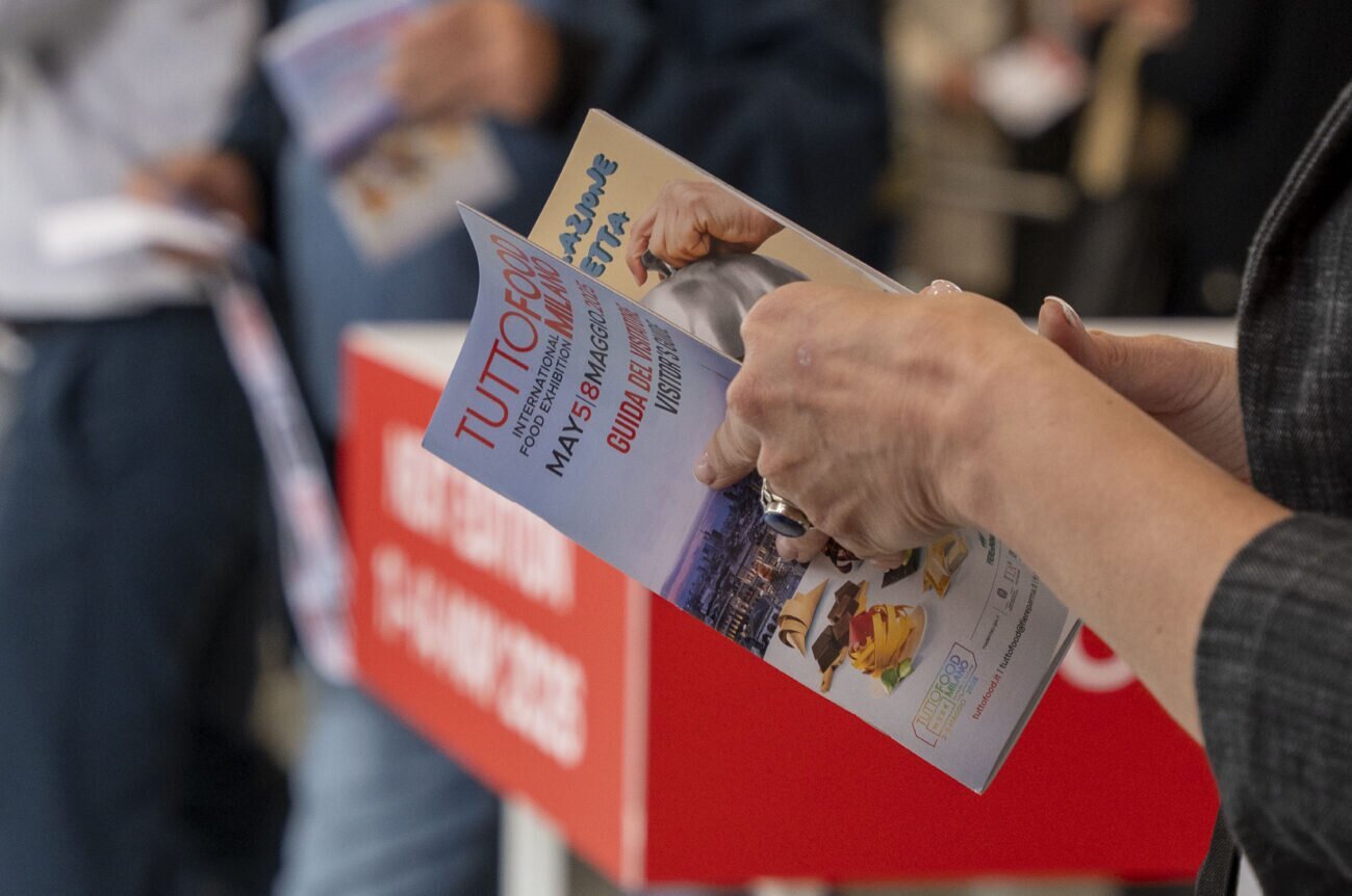 Person holding a TuttoFOOD Milano brochure.