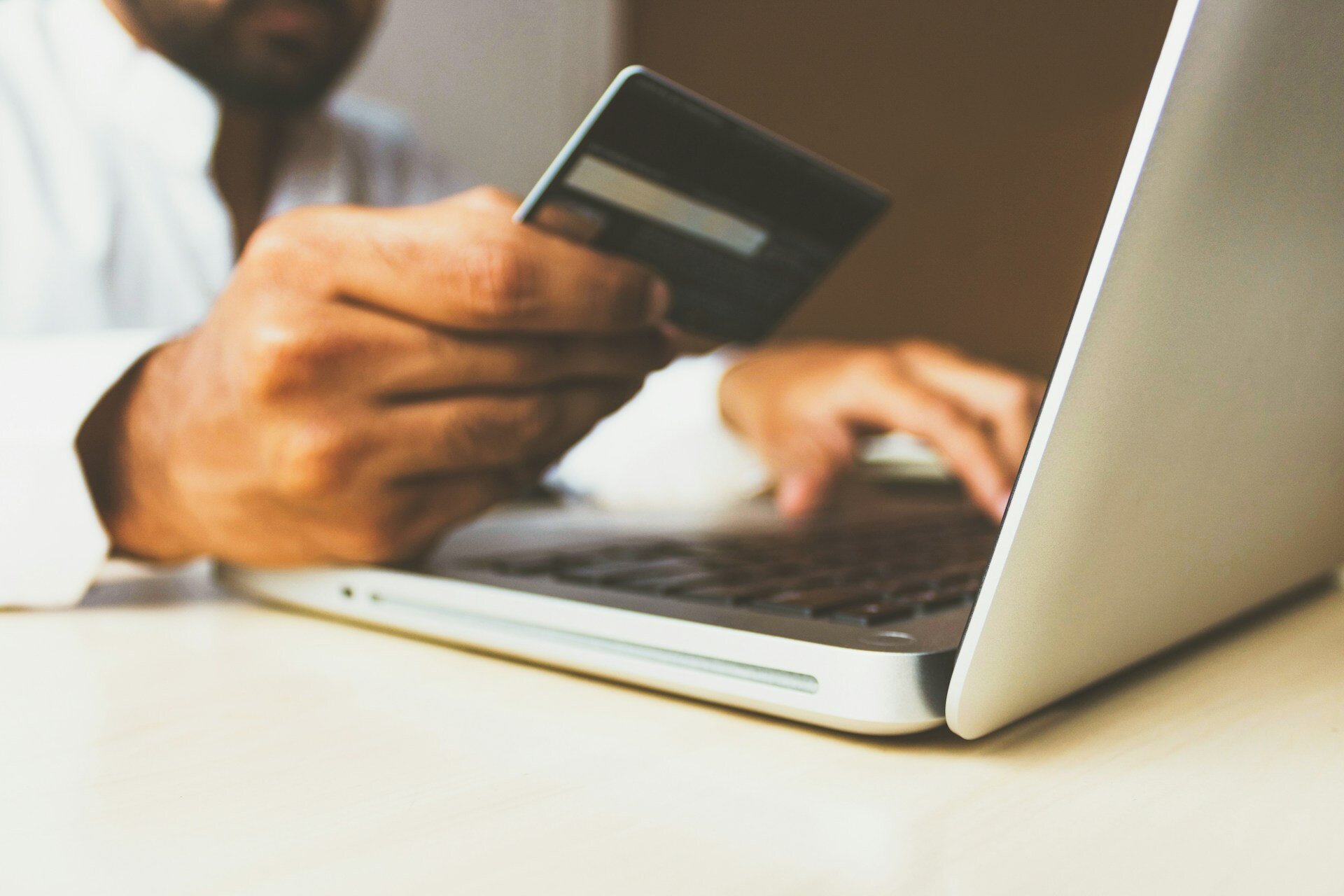 person holding credit card on laptop computer.